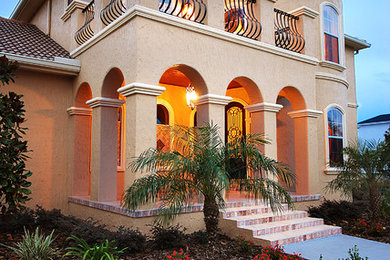 Diseño de fachada marrón mediterránea grande de dos plantas con revestimiento de estuco y tejado a cuatro aguas