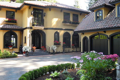 Inspiration for a large mediterranean yellow two-story adobe exterior home remodel in Vancouver with a tile roof