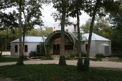 Foto della villa grande grigia country a due piani con rivestimenti misti, tetto a capanna e copertura in metallo o lamiera