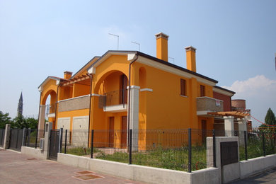 Diseño de fachada amarilla minimalista grande de tres plantas con revestimiento de aglomerado de cemento y tejado a la holandesa