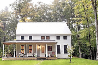 Modelo de fachada de casa gris de estilo de casa de campo de tamaño medio de dos plantas con revestimiento de vinilo, tejado a dos aguas y tejado de metal