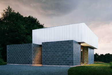 Foto de fachada de casa gris minimalista pequeña de una planta con revestimiento de hormigón, tejado plano y tejado de varios materiales
