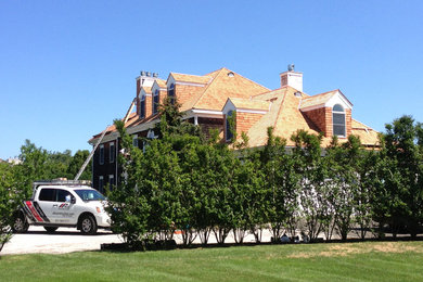 Modelo de fachada marrón clásica grande de tres plantas con revestimiento de madera y tejado a dos aguas