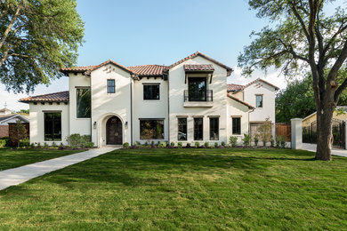 Inspiration for a large mediterranean yellow two-story stucco house exterior remodel in Dallas with a hip roof and a tile roof