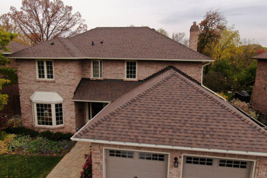 Modelo de fachada de casa beige tradicional de tamaño medio de dos plantas con revestimiento de ladrillo, tejado a cuatro aguas y tejado de teja de madera