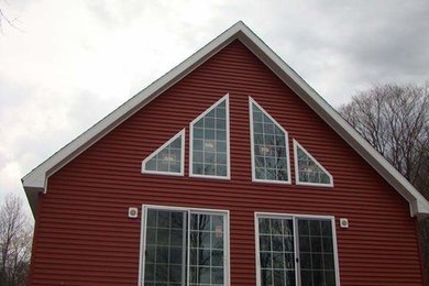 Example of a mid-sized country red two-story vinyl gable roof design in New York