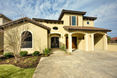 Example of a large tuscan yellow one-story stucco exterior home design in Austin