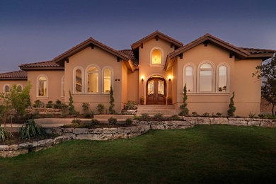 Example of a large tuscan beige one-story concrete exterior home design in Austin