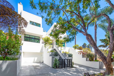 Example of a large minimalist white three-story stucco exterior home design in Los Angeles