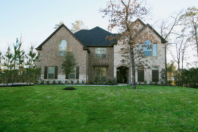 Large tuscan beige two-story stone exterior home photo in Houston with a hip roof