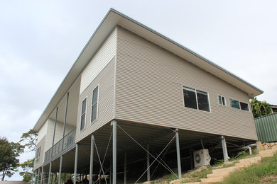 Imagen de fachada beige actual de tamaño medio de una planta con revestimiento de metal y tejado plano