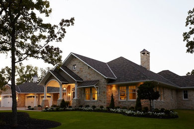 Example of a mid-sized classic beige one-story stone house exterior design in Other with a hip roof and a shingle roof
