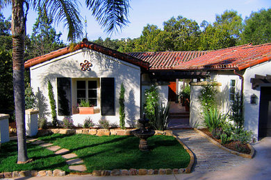Medium sized and white mediterranean bungalow render detached house in Santa Barbara with a half-hip roof and a tiled roof.