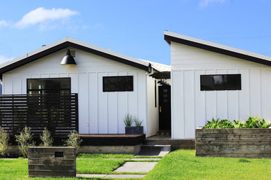 Mid-sized country white one-story concrete fiberboard house exterior photo in Los Angeles with a shed roof and a metal roof