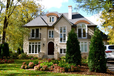 Foto della facciata di una casa grande beige classica a due piani con rivestimento in pietra
