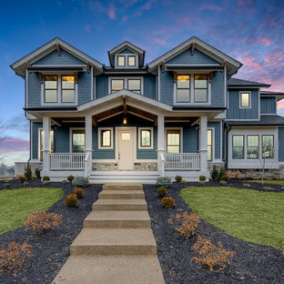 Réalisation d'une façade de maison bleue craftsman à un étage avec un revêtement en vinyle et un toit en shingle.