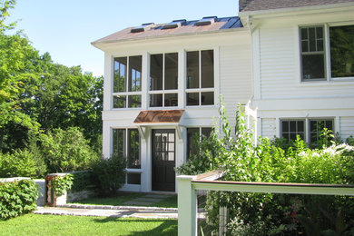 Foto della villa grande bianca classica a due piani con rivestimento con lastre in cemento, tetto a capanna e copertura a scandole