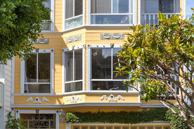 This is an example of a large and yellow victorian house exterior in San Francisco with three floors and a flat roof.