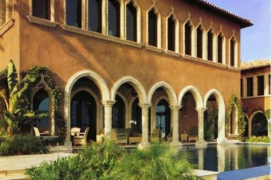 Inspiration for a large mediterranean beige two-story stucco house exterior remodel in Los Angeles with a hip roof and a tile roof