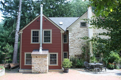 Cette image montre une grande façade de maison rouge rustique en béton à un étage avec un toit à deux pans.