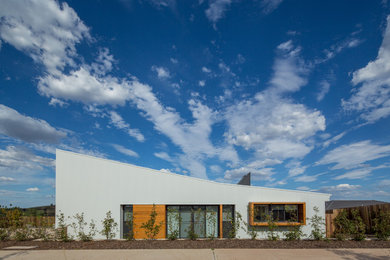 На фото: одноэтажный, белый частный загородный дом среднего размера в современном стиле с облицовкой из металла