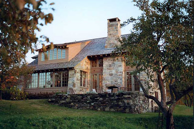 Example of a large arts and crafts gray three-story stone house exterior design in Burlington