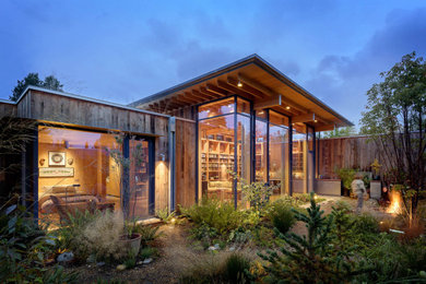 シアトルにあるコンテンポラリースタイルのおしゃれな家の外観 (ガラスサイディング、緑化屋根) の写真