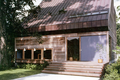 Diseño de fachada de casa actual de tamaño medio de tres plantas con revestimiento de madera, tejado de un solo tendido y tejado de metal