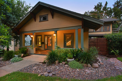 Diseño de fachada de casa amarilla de estilo americano de dos plantas con revestimiento de madera, tejado a dos aguas y tejado de teja de madera