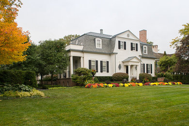 Foto della facciata di una casa grande bianca classica a due piani con rivestimento in legno e tetto a mansarda