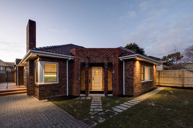 Photo of a large and red retro bungalow brick house exterior in Melbourne with a hip roof.