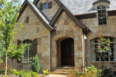 Ejemplo de fachada de casa gris de estilo americano de tamaño medio de tres plantas con revestimiento de piedra, tejado a dos aguas y tejado de teja de madera