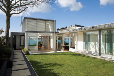 Imagen de fachada de casa gris minimalista de tres plantas con revestimiento de metal, tejado plano y tejado de varios materiales