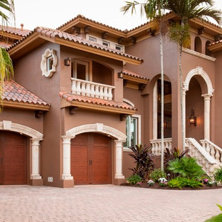 Foto de fachada de casa marrón, mediterránea, grande, de tres plantas, con revestimiento de hormigón, tejado a dos aguas y tejado de teja de barro
