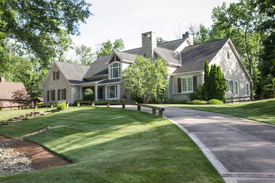 Cette photo montre une grande façade de maison beige chic en pierre de plain-pied avec un toit à deux pans et un toit en shingle.