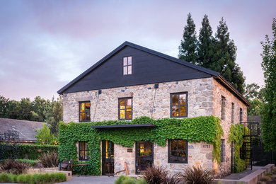 Modelo de fachada de casa beige rural de dos plantas con revestimiento de piedra y tejado a cuatro aguas