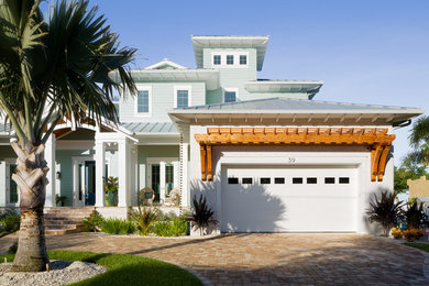 Esempio della villa grande blu stile marinaro a due piani con rivestimenti misti, tetto a padiglione e copertura in metallo o lamiera