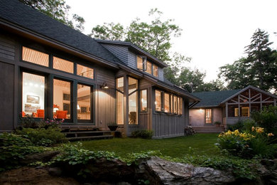 Modelo de fachada de casa beige rural grande de dos plantas con revestimiento de madera, tejado a dos aguas y tejado de teja de madera