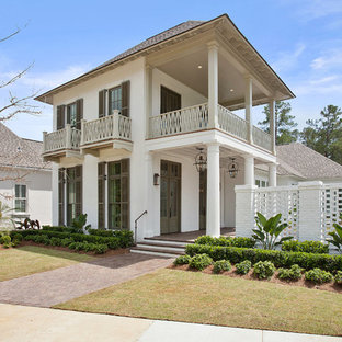 Inspiration for a mid-sized coastal beige two-story stucco exterior home remodel in New Orleans with a hip roof
