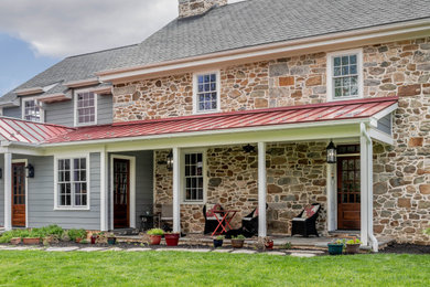 Inspiration for a farmhouse two-story stone exterior home remodel in Philadelphia with a mixed material roof