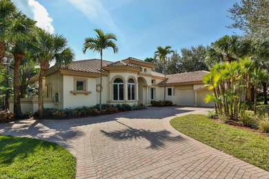 Large tuscan beige two-story stucco house exterior photo in Miami with a hip roof and a tile roof