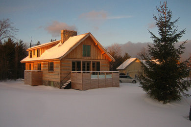 Modelo de fachada beige moderna de tamaño medio de dos plantas con revestimiento de madera y tejado a dos aguas