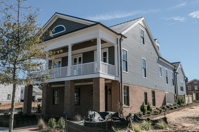 Modelo de fachada de casa gris tradicional grande de tres plantas con revestimiento de aglomerado de cemento, tejado de un solo tendido y tejado de metal