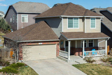 Cette photo montre une façade de maison beige chic de taille moyenne et à un étage avec un toit à quatre pans et un toit en shingle.