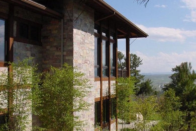Imagen de fachada de casa minimalista de tamaño medio de dos plantas con revestimiento de piedra y tejado plano