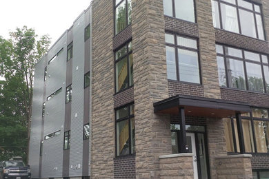 This is an example of a gey contemporary house exterior in Ottawa with three floors and metal cladding.