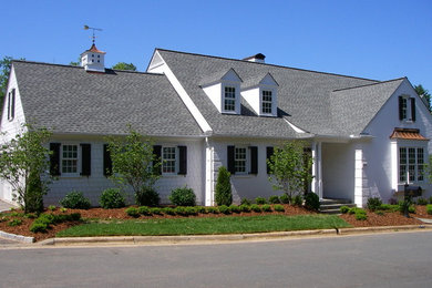 Modelo de fachada blanca clásica de tamaño medio de dos plantas con revestimiento de vinilo y tejado a dos aguas