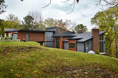 Bild på ett stort funkis grått hus i flera nivåer, med blandad fasad, pulpettak och tak i mixade material
