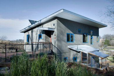 Modelo de fachada de casa gris actual de tamaño medio de dos plantas con revestimiento de estuco y tejado de un solo tendido