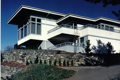 Diseño de fachada de casa blanca clásica renovada de tamaño medio de dos plantas con revestimiento de estuco y tejado plano